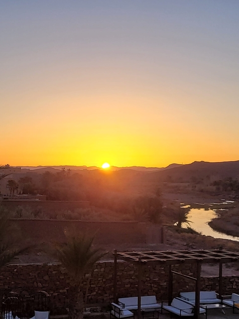 Sunset over mountainous terrain with a small stream.