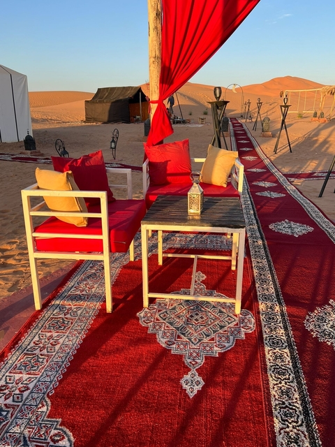 Stylish seating arrangement in a desert camp with carpets and pillows.