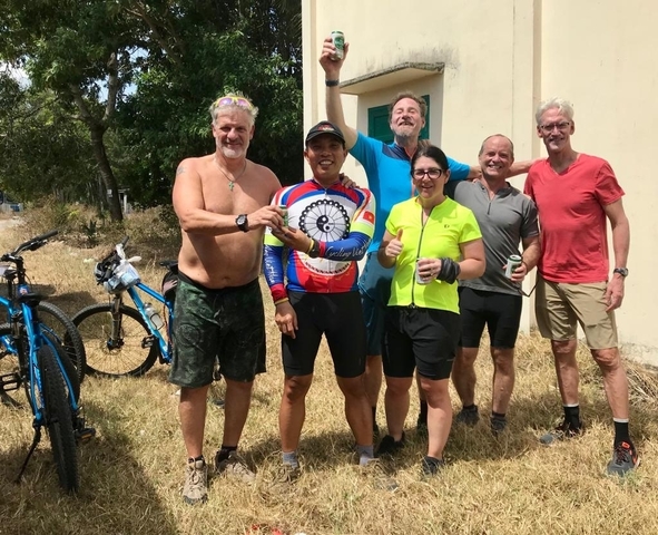       Group of cyclists posing for a photo outdoors.
  