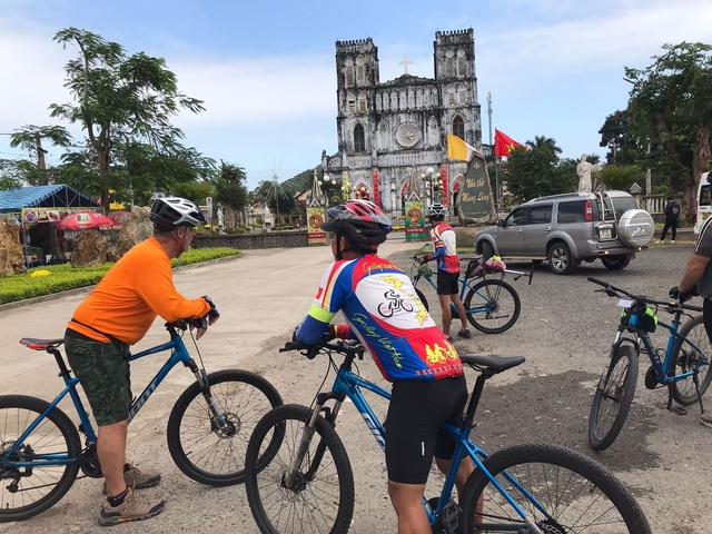 Cyclists with bicycles near a church.