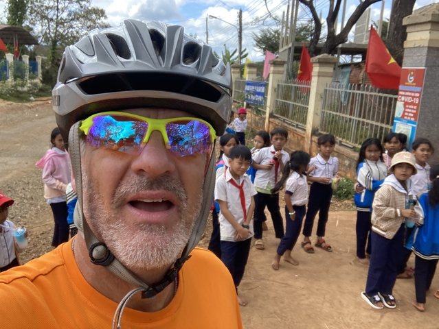       Group of children with cyclist in background.
  