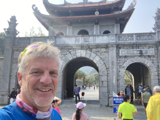       Person taking a selfie in front of historical stone gate.
  