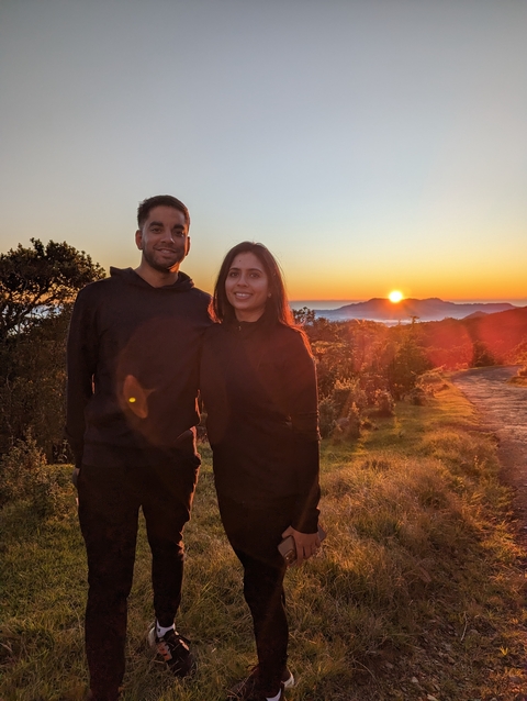       Couple in front of a sunset with mountains in the background.
  