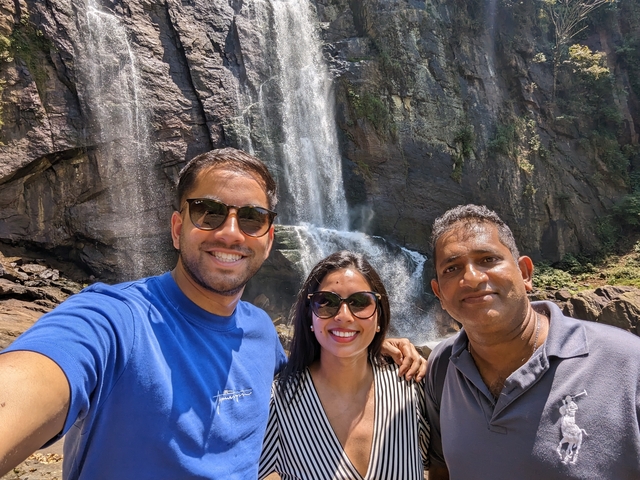       Three people posing in front of a large waterfall.
  
