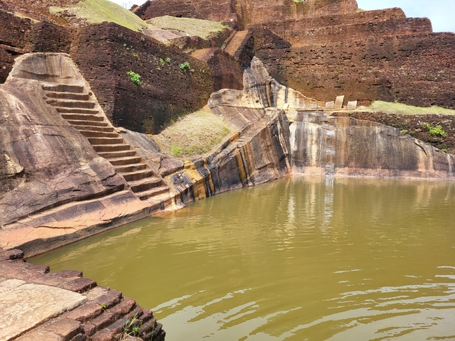       Ancient stepped pool surrounded by stone walls.
  