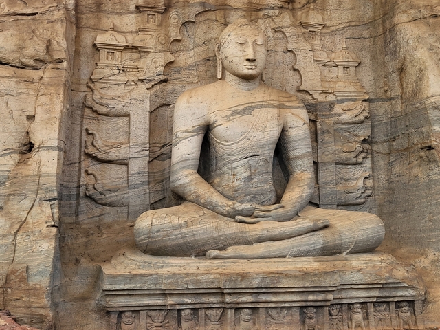       An ancient stone-carved buddha seated in meditation.
  