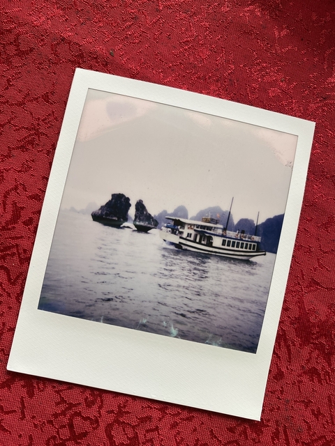       A Polaroid photo of a boat with rocky outcrops.
  