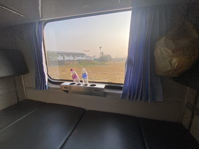 View out of a train window with two water bottles on the sill.