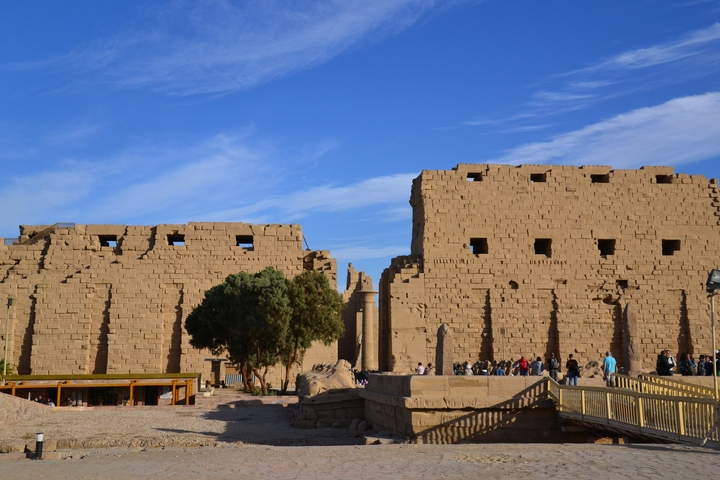 The ruins of an ancient Egyptian temple with tourists exploring.