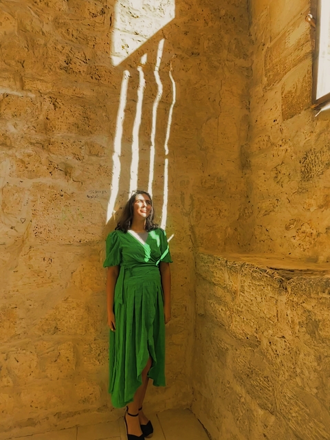       Woman standing inside an ancient limestone structure.
  