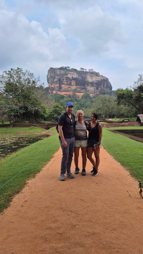 Three people posing in front of Sigiriya Rock.