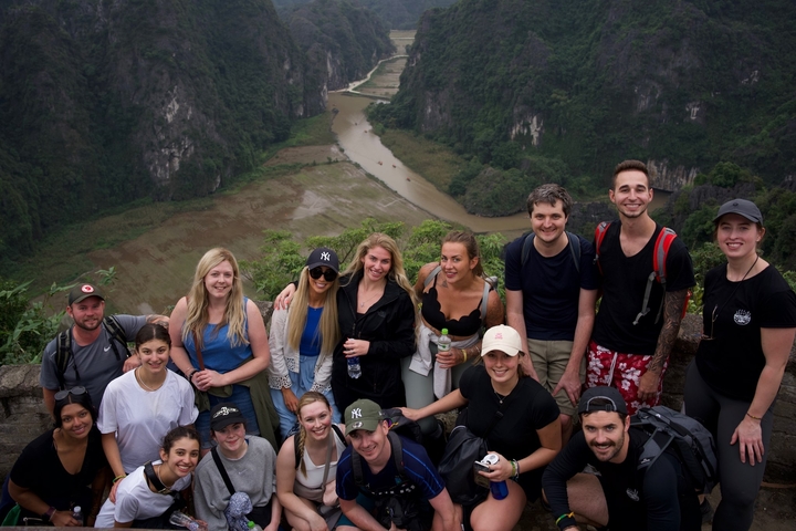       Group posing with a scenic river valley backdrop.
  