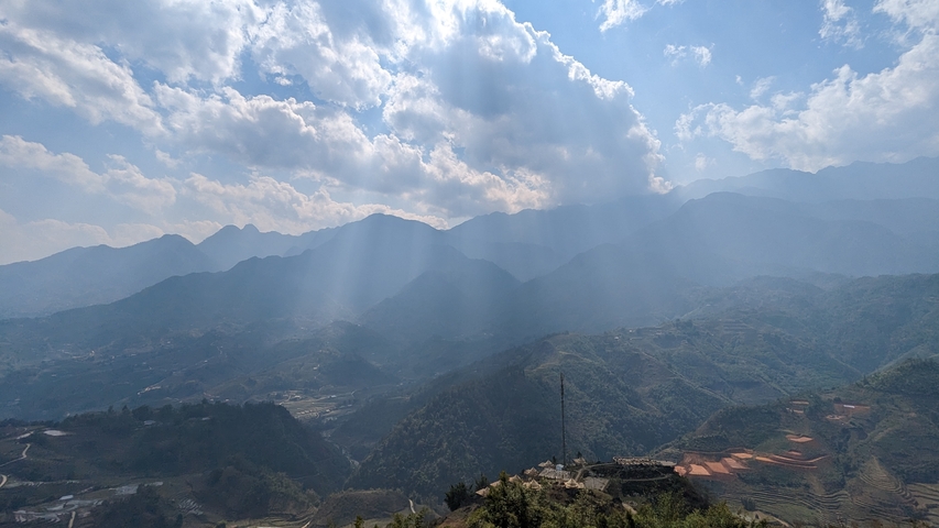       Scenic view of misty mountains with rays of sunlight piercing through clouds.
  