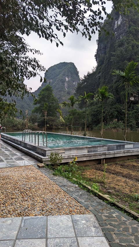       A pool with a scenic view of mountains and trees surrounding it.
  