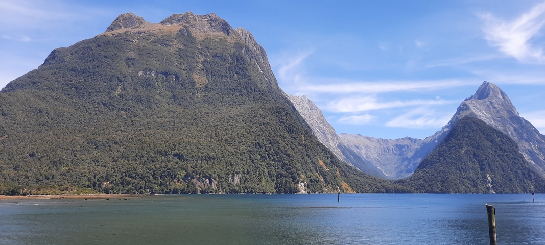 Magnificent mountains rising from a fjord with a blue sky.