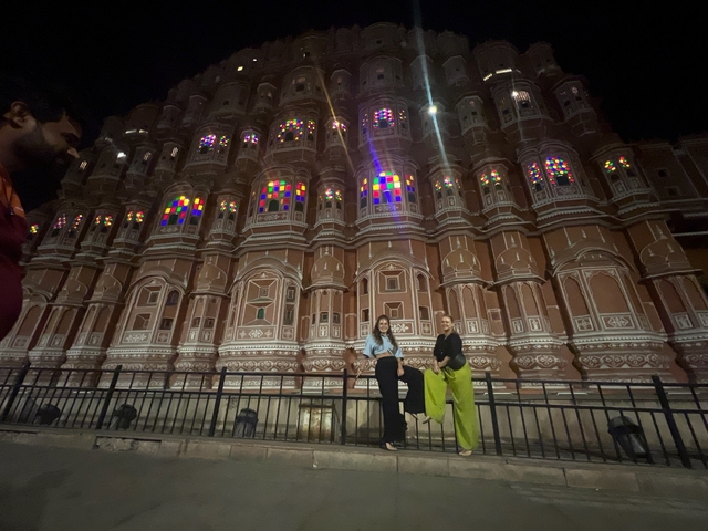 Two people standing in front of a beautifully lit building at night.