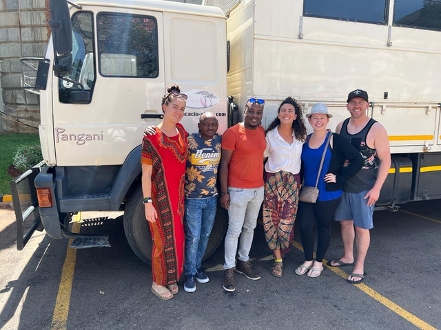 Group of people in front of a truck named 'Pangani'.