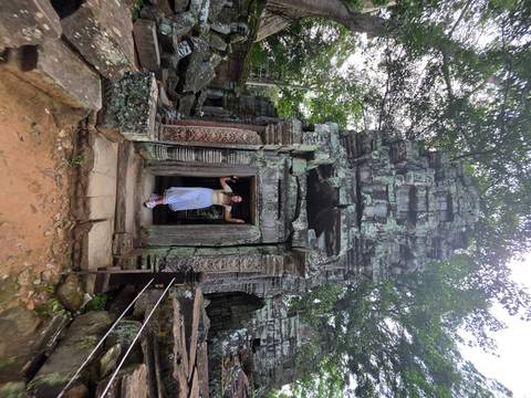 Woman posing within an overgrown temple entrance.