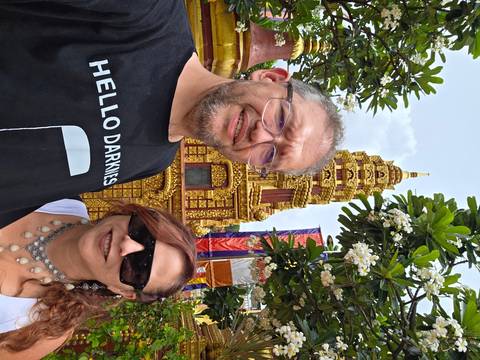 Two individuals posing in front of a golden temple structure.