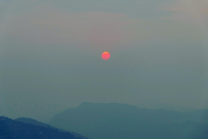       Atmospheric shot of the sun setting over distant hills.
  