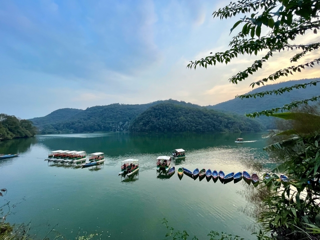       Serene lakeside view with colorful boats.
  