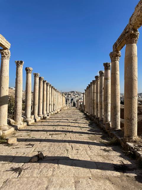       Ancient colonnade with city view in the distance.
  