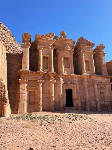 Ancient rock facade in Petra under a bright sky.
