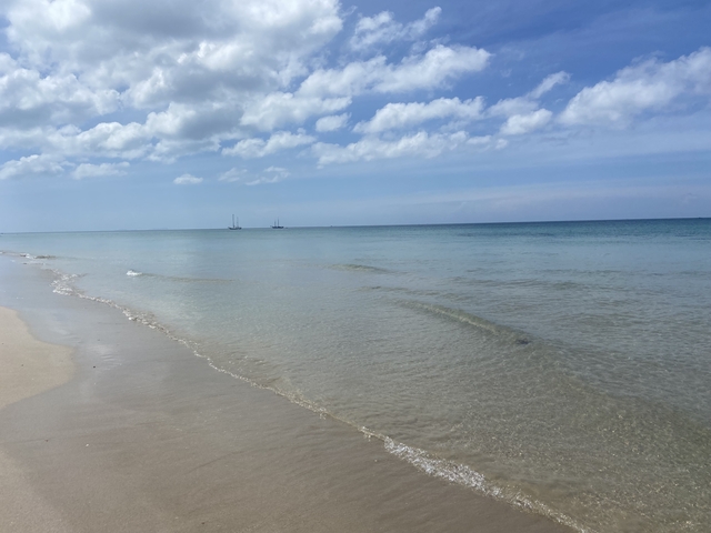       Calm sea facing an open horizon under a clear sky.
  
