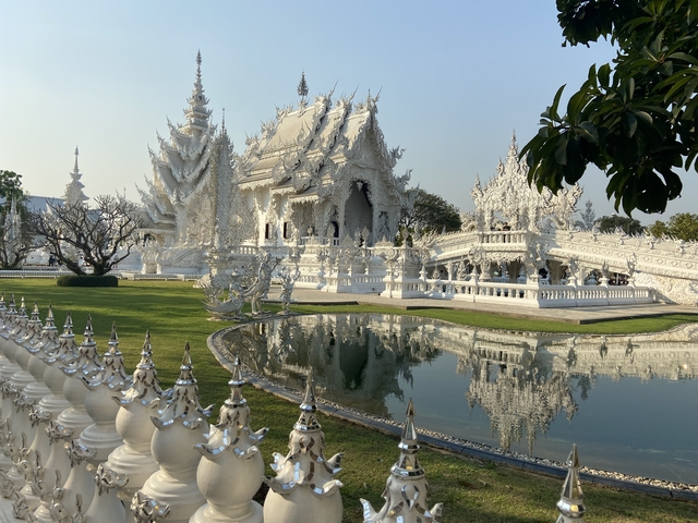       White temple with intricate architecture and reflection in the water.
  
