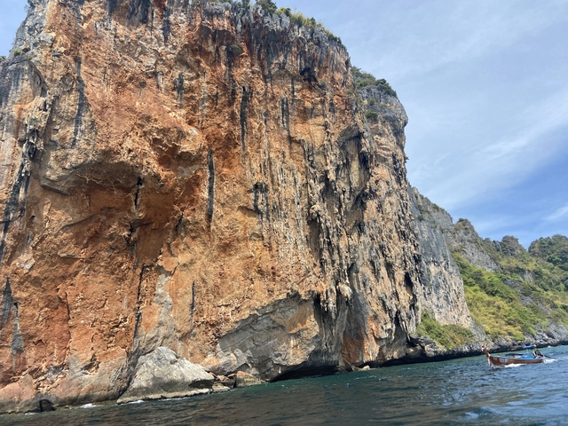       Large rocky cliff face by the water.
  