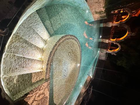 Outdoor pool with decorative stonework at night.