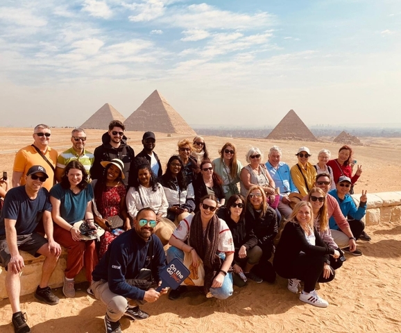Group of people posing with the Pyramids of Giza.