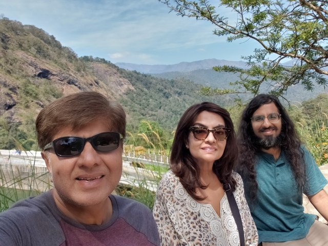 Group of three people posing with mountainous landscape.