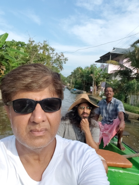 Two men on a boat in a canal surrounded by greenery.