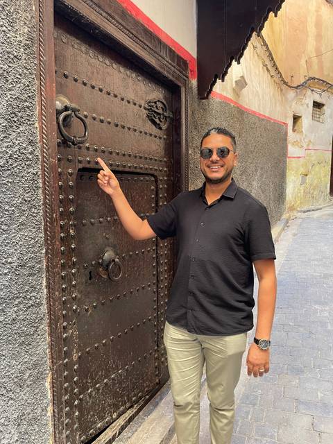 Person posing next to a large, ornate door.