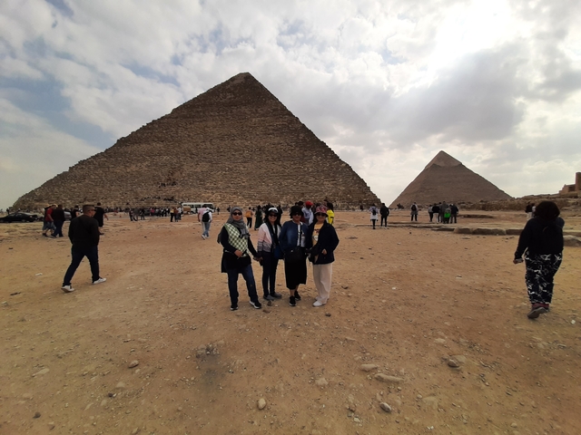 A group posing in front of pyramids in a desert.