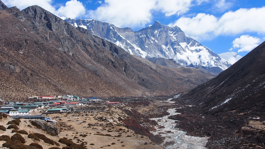       Mountain landscape with a village nestled in the valley, surrounded by snow-peaked mountains.
  