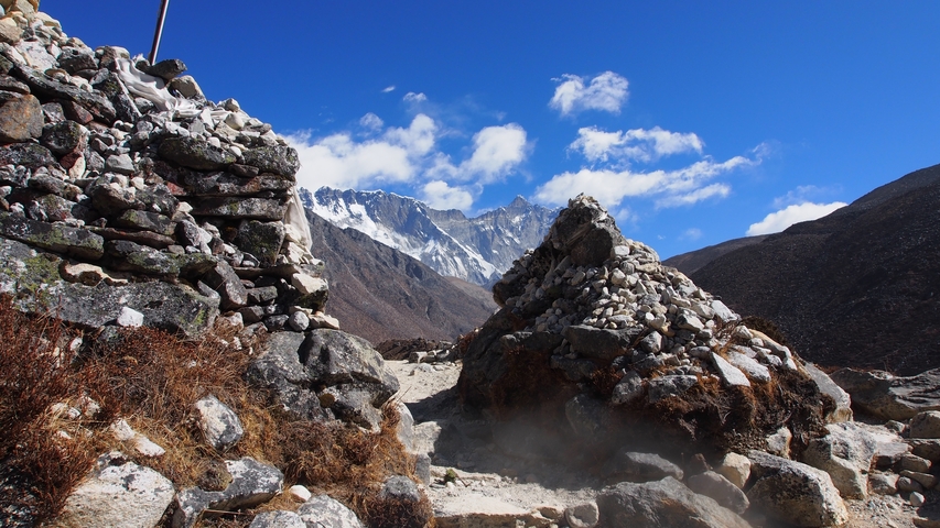       Prayer flags and stone structures in a mountainous landscape.
  