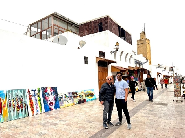       People walking on a street lined with art and shops.
  