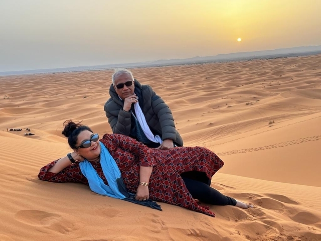       Couple posing on sand dunes during sunset.
  