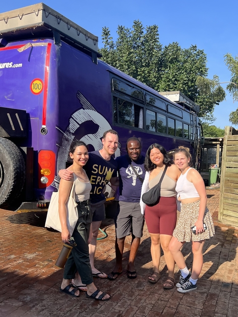 Group of people smiling in front of a large bus.