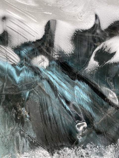       Close-up view of textured icy surface featuring blue and black colors.
  