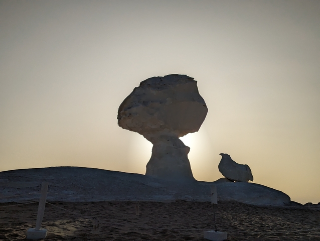 A rock formation resembling a mushroom with a sunset backdrop.