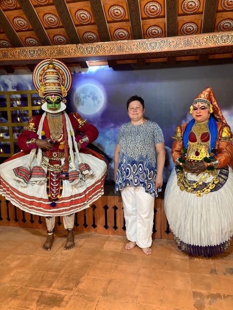       A person with traditional performers in colorful costumes.
  