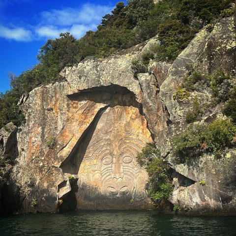 A large rock carving depicting an intricate face design.