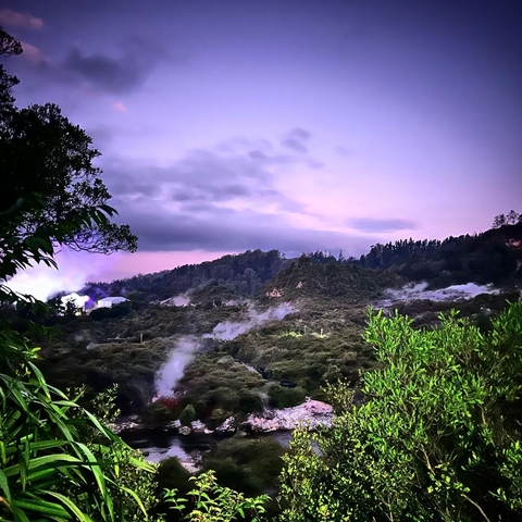 A mystical, mountainous landscape with steam at dusk.