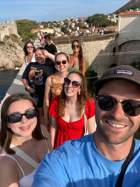 Group selfie of smiling people with a scenic view in the background.