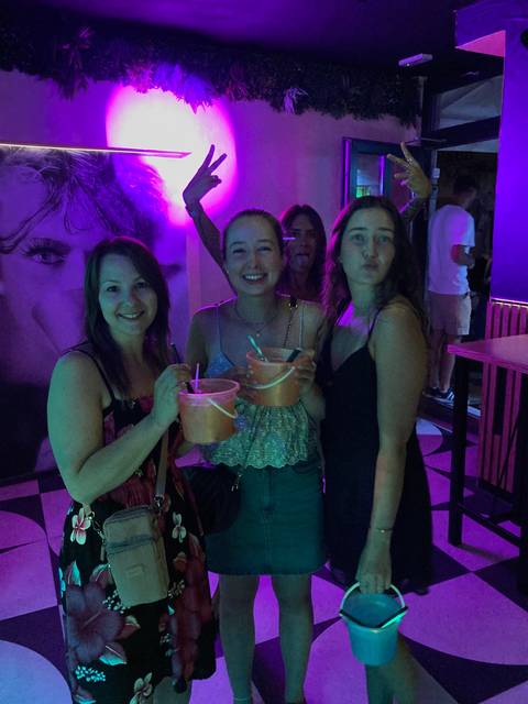Women posing with drinks in a nightclub setting.