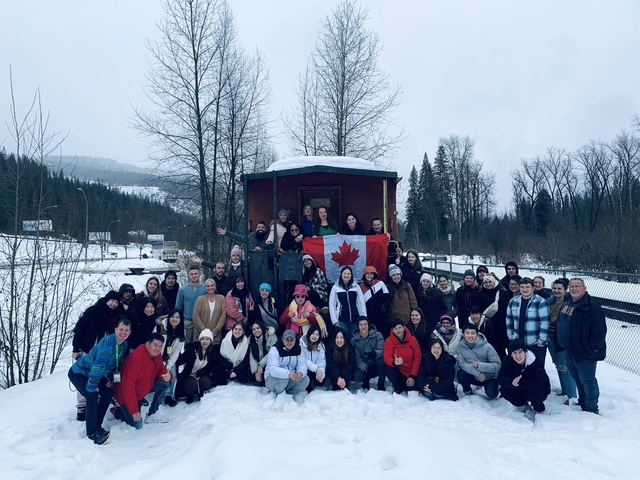       Large group photo in a snowy setting holding a Canadian flag.
  