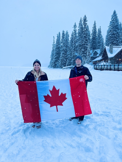       Couple holding a Canadian flag in a snowy landscape.
  